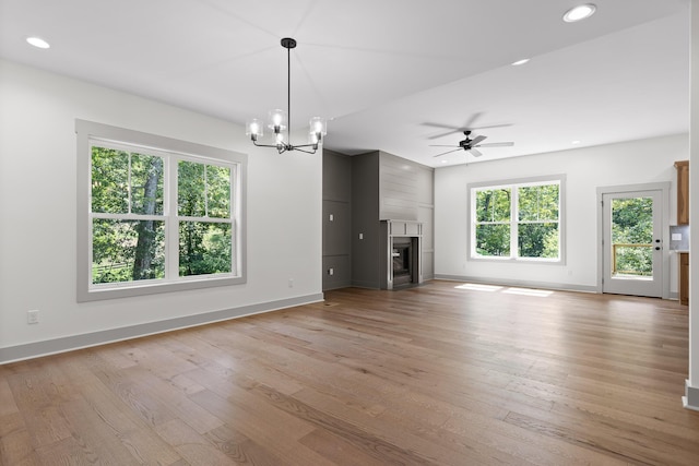 unfurnished living room featuring ceiling fan with notable chandelier and light hardwood / wood-style flooring