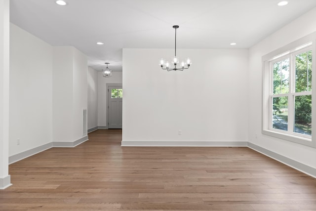 spare room featuring a notable chandelier and light hardwood / wood-style floors