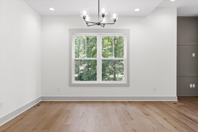 unfurnished dining area with an inviting chandelier and light hardwood / wood-style flooring