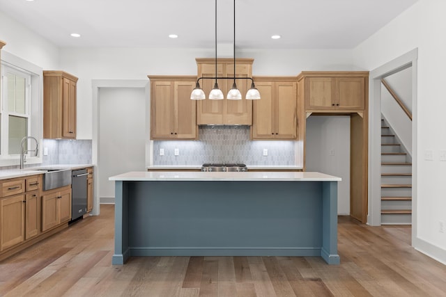 kitchen with sink, hanging light fixtures, light wood-type flooring, and a kitchen island