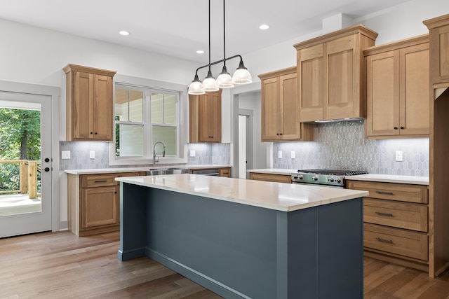 kitchen with a wealth of natural light, stove, hanging light fixtures, a kitchen island, and light hardwood / wood-style flooring