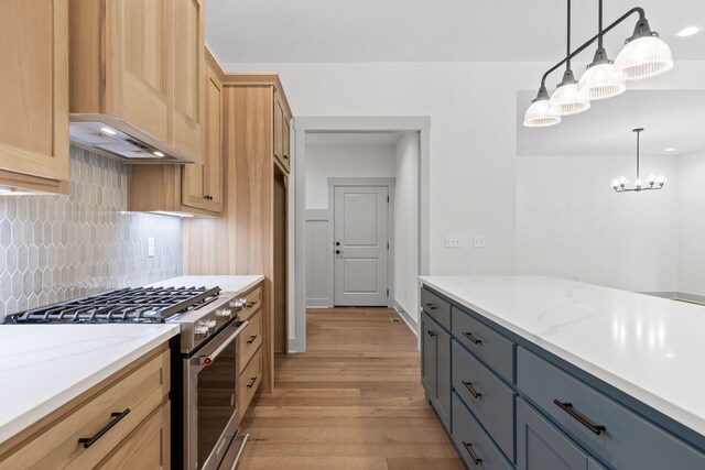 kitchen featuring high end stove, gray cabinets, backsplash, decorative light fixtures, and light stone countertops