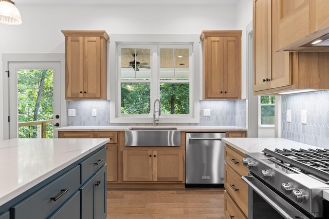 kitchen featuring light stone countertops, custom exhaust hood, stainless steel appliances, sink, and hanging light fixtures