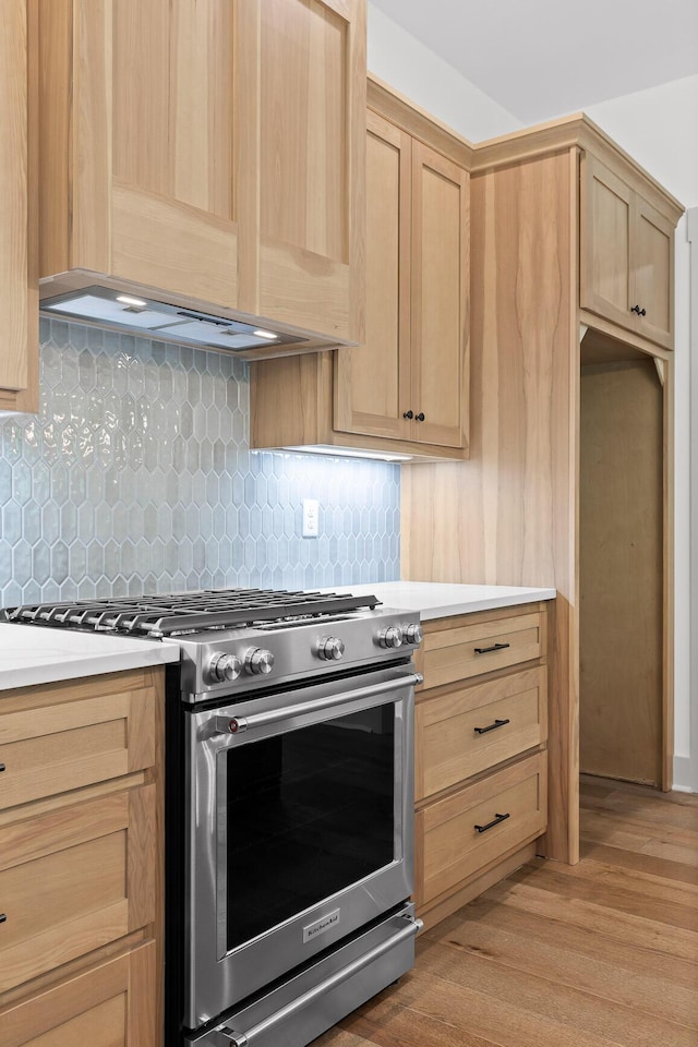 kitchen featuring premium range hood, light brown cabinets, tasteful backsplash, gas range, and light hardwood / wood-style flooring