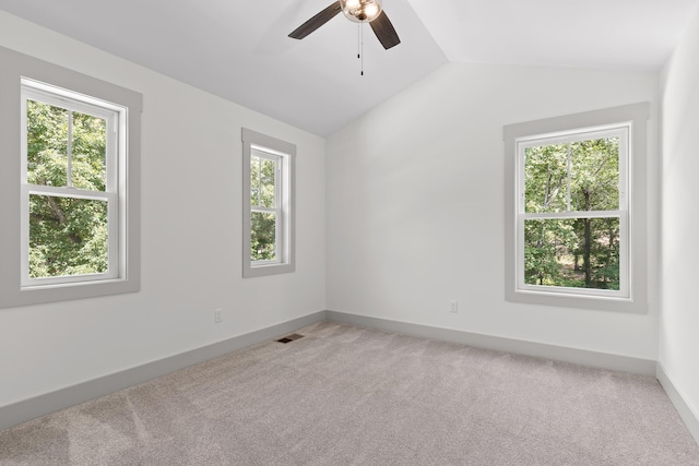 carpeted spare room featuring vaulted ceiling, ceiling fan, and a healthy amount of sunlight