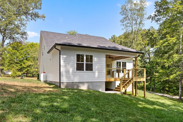 rear view of house with ceiling fan, a wooden deck, and a lawn