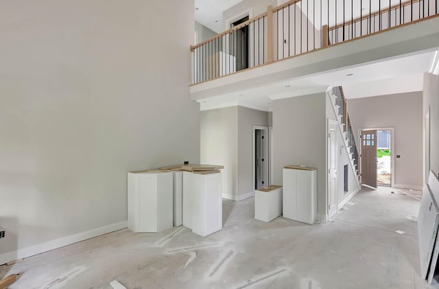interior space featuring baseboards and a high ceiling