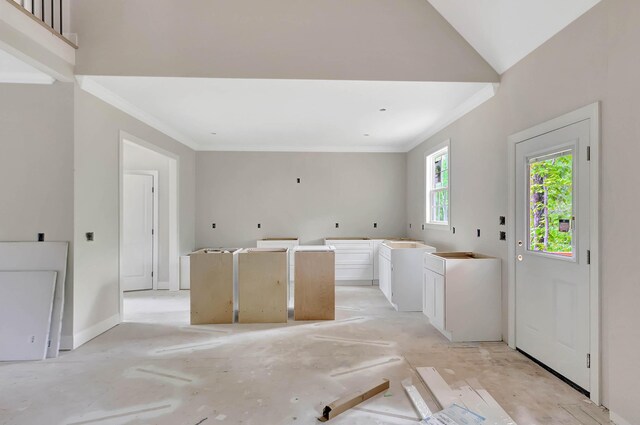 interior space featuring baseboards, a center island, white cabinets, and crown molding