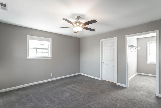 unfurnished bedroom featuring dark colored carpet, a closet, and ceiling fan