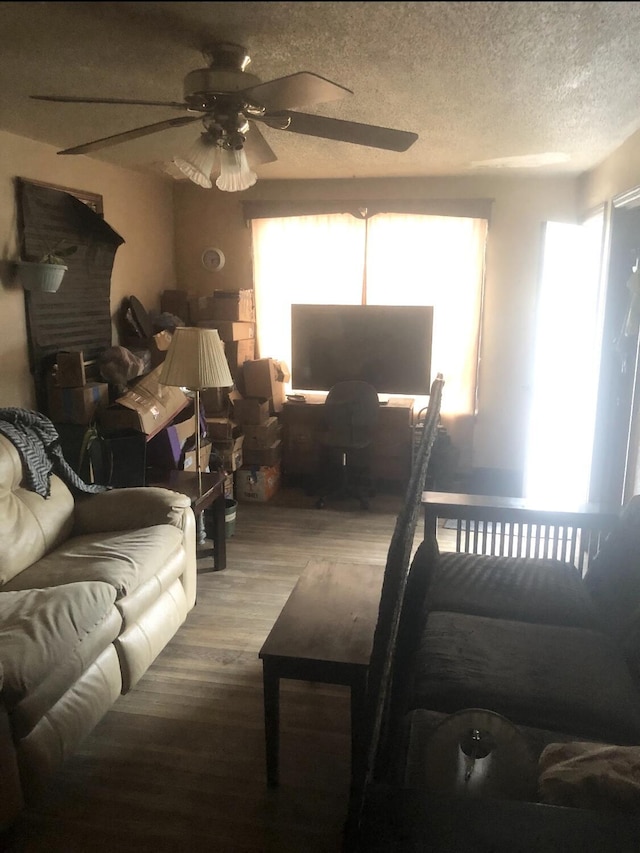 living room with ceiling fan, a textured ceiling, and hardwood / wood-style flooring