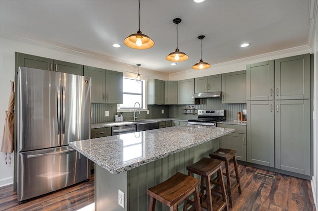 kitchen featuring appliances with stainless steel finishes, sink, decorative light fixtures, light stone counters, and a kitchen island