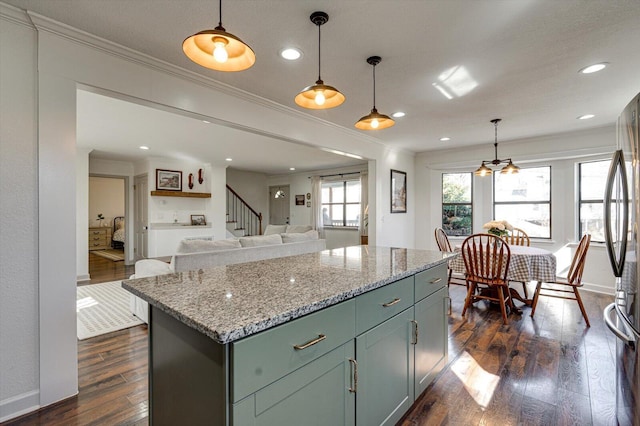 kitchen with dark wood-type flooring, crown molding, and a kitchen island