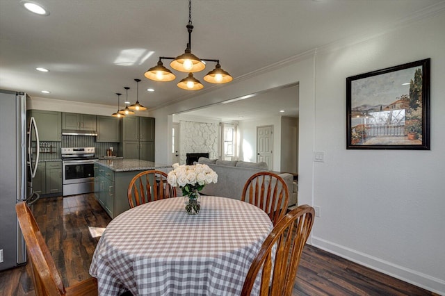 dining space with dark hardwood / wood-style floors, crown molding, and a fireplace