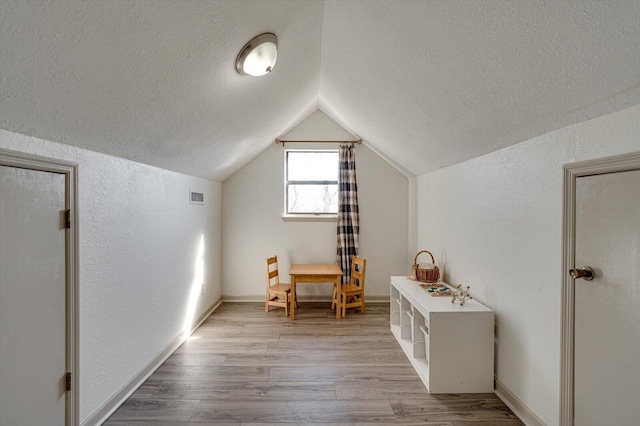 additional living space featuring light wood-type flooring and lofted ceiling