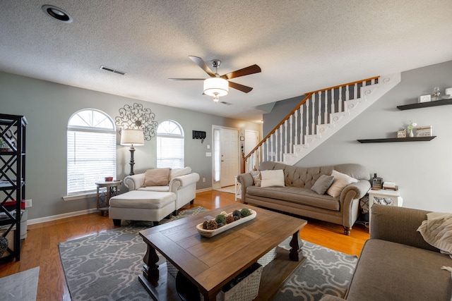 living room with hardwood / wood-style flooring, ceiling fan, and a textured ceiling