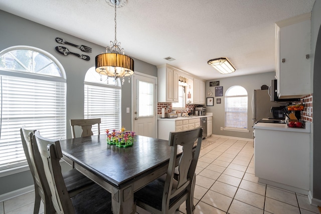 tiled dining area featuring sink, a wealth of natural light, and a textured ceiling