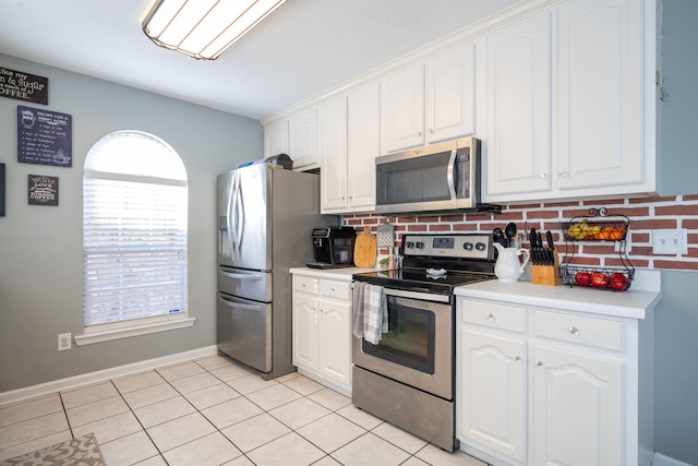 kitchen featuring light tile patterned flooring, backsplash, white cabinetry, and appliances with stainless steel finishes