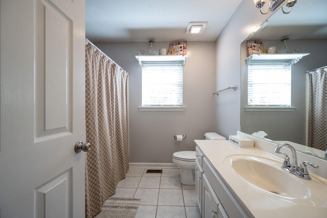 bathroom with a healthy amount of sunlight, toilet, tile patterned floors, and vanity