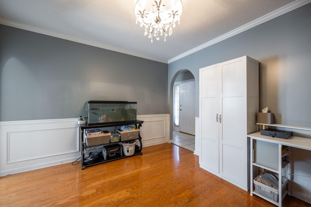 office area featuring light wood-type flooring, a chandelier, ornamental molding, and a textured ceiling