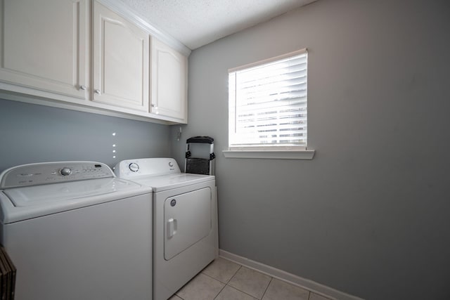 clothes washing area featuring cabinets, a textured ceiling, light tile patterned floors, and washing machine and dryer