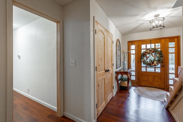 foyer entrance with dark hardwood / wood-style floors and a notable chandelier