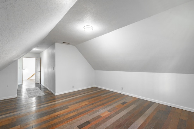 additional living space featuring lofted ceiling, dark hardwood / wood-style floors, and a textured ceiling