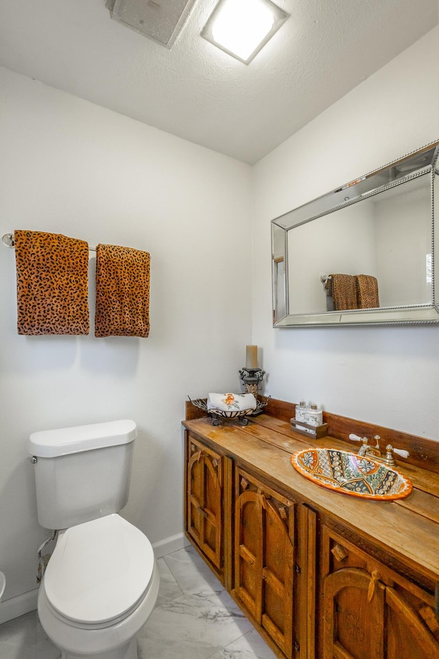 bathroom with vanity, a textured ceiling, and toilet