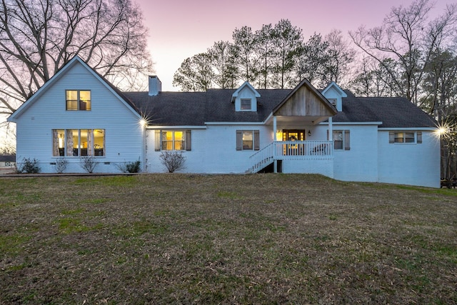 back house at dusk with a lawn