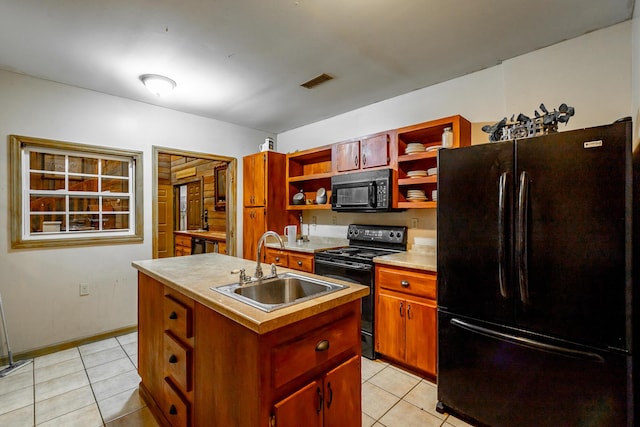 kitchen featuring light tile patterned flooring, sink, a kitchen island with sink, and black appliances