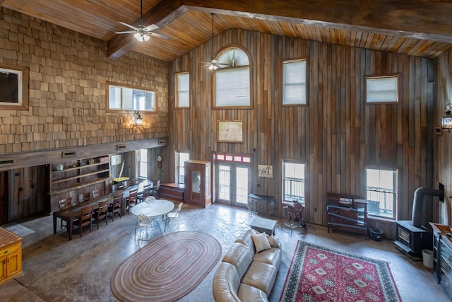 living room with high vaulted ceiling, wooden ceiling, wooden walls, ceiling fan, and beam ceiling