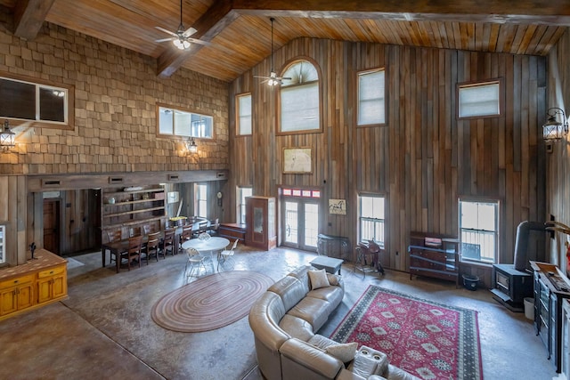 living room featuring high vaulted ceiling, wooden ceiling, wooden walls, ceiling fan, and beam ceiling