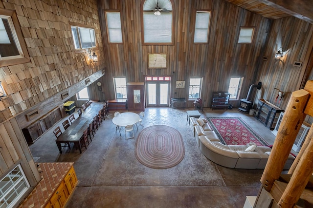 unfurnished living room with a towering ceiling and wooden walls