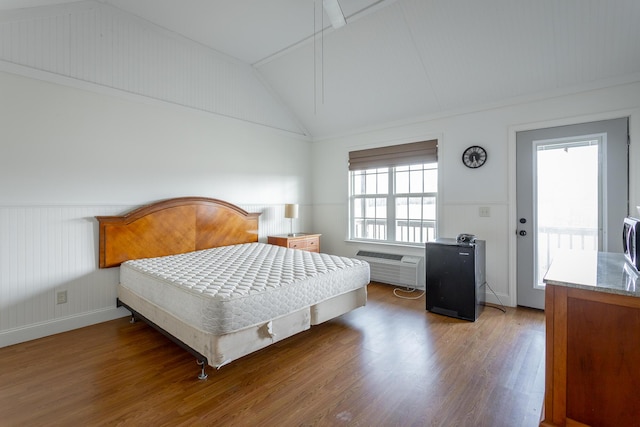 bedroom with vaulted ceiling, a wall mounted AC, and hardwood / wood-style floors