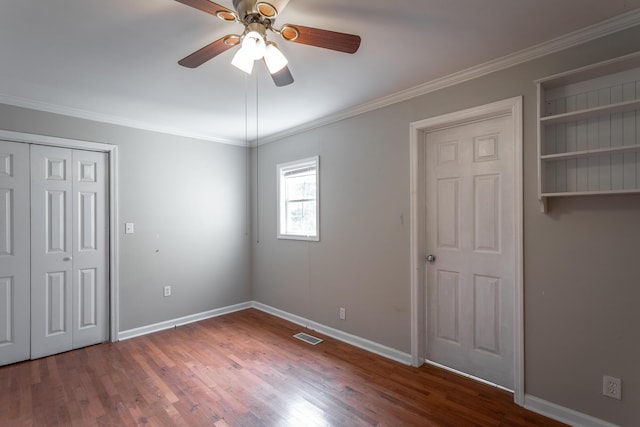 unfurnished bedroom featuring ceiling fan, dark wood-type flooring, and crown molding