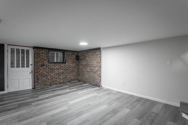 interior space with hardwood / wood-style floors and brick wall