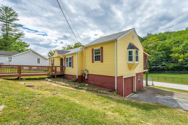 view of side of home featuring a deck, a lawn, and a garage