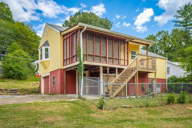 rear view of house featuring a garage, a sunroom, and a lawn