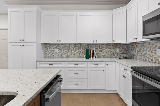 kitchen featuring stainless steel appliances, tasteful backsplash, light stone counters, light hardwood / wood-style floors, and white cabinets