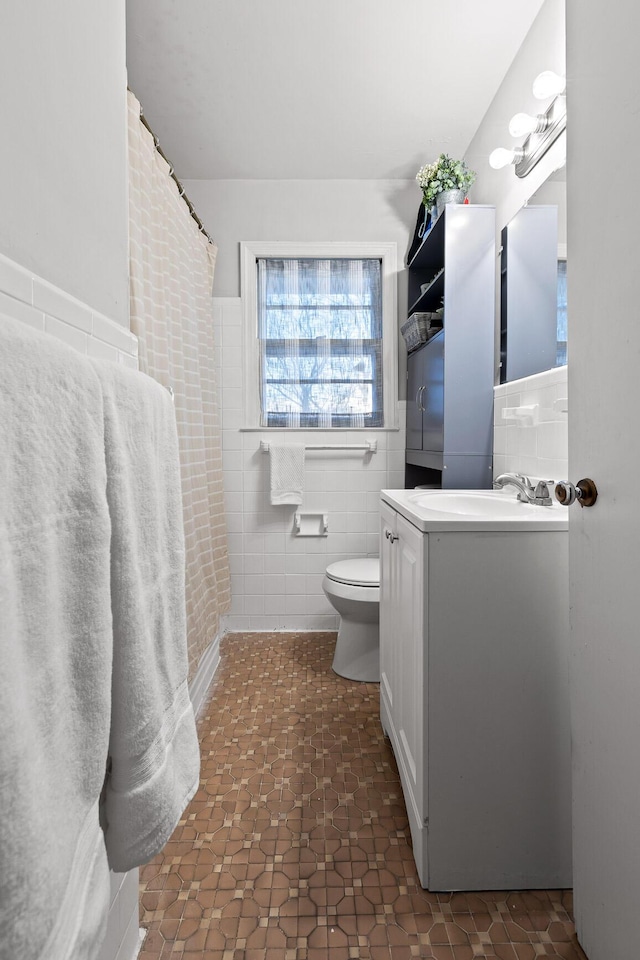 bathroom with vanity, tile walls, and toilet