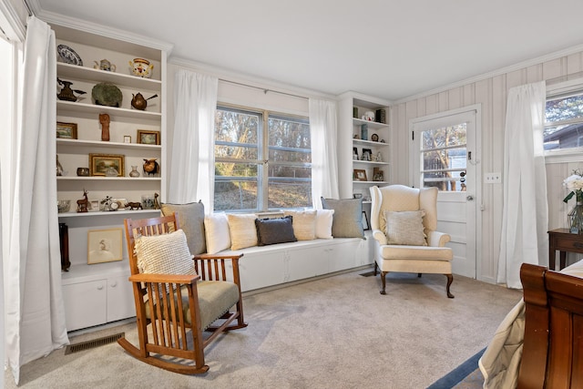 sitting room with ornamental molding and light colored carpet