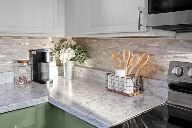 room details featuring white cabinetry, tasteful backsplash, stainless steel appliances, and green cabinets