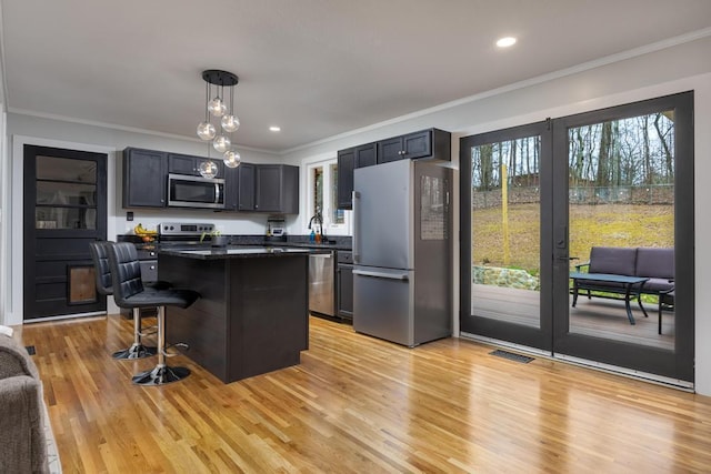 kitchen with a kitchen island, a kitchen bar, a wealth of natural light, and appliances with stainless steel finishes