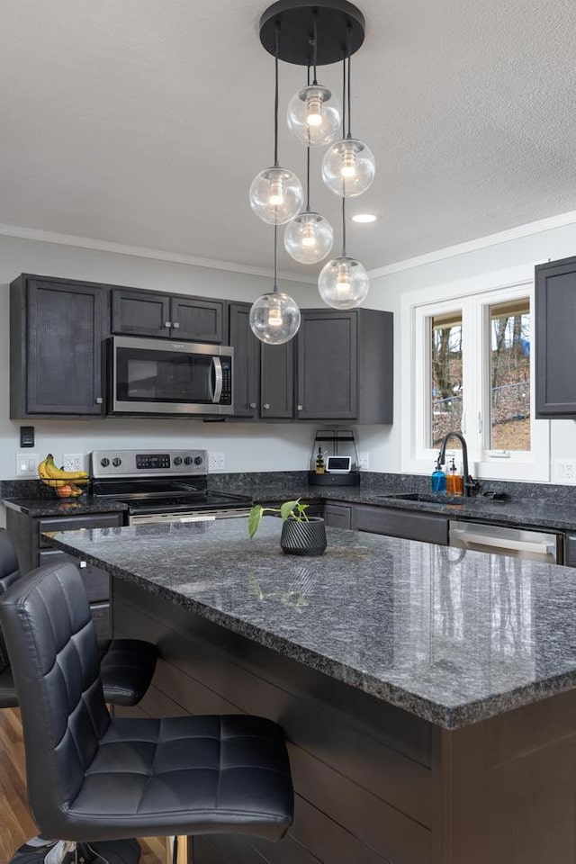 kitchen with decorative light fixtures, sink, dark hardwood / wood-style floors, dark stone countertops, and stainless steel appliances