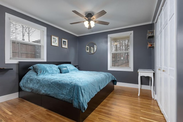 bedroom featuring ceiling fan, light hardwood / wood-style flooring, crown molding, and multiple windows