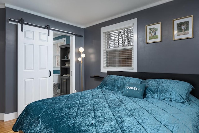 bedroom featuring ensuite bath, a barn door, crown molding, and wood-type flooring