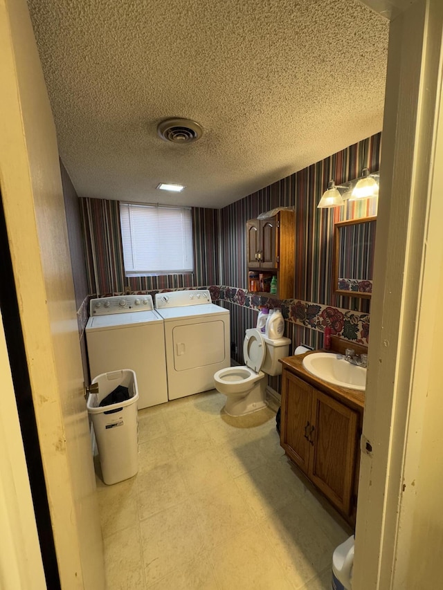 bathroom featuring toilet, a textured ceiling, a tub to relax in, vanity, and independent washer and dryer