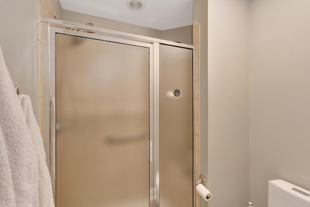 bathroom featuring a shower with door and toilet