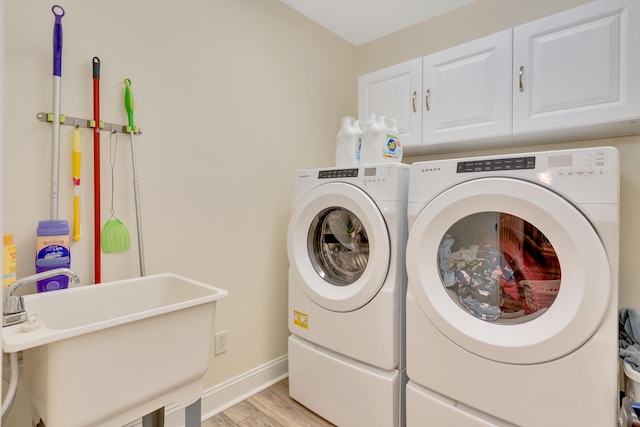 laundry room featuring cabinets, light hardwood / wood-style floors, sink, and washer and dryer