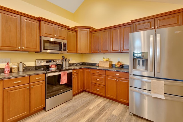 kitchen with lofted ceiling, appliances with stainless steel finishes, and light hardwood / wood-style flooring