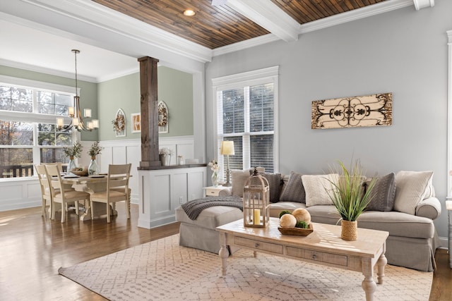 living room with hardwood / wood-style floors, decorative columns, ornamental molding, wooden ceiling, and beam ceiling